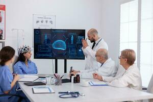 Neurologist showing digital radiography to medical coworkers analysing brain illness presentation using high tech in meeting room. Hospital team analyzing ill treatment examining healthcare expertise photo