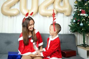 alegre Navidad 2024 concepto madre y niño Decorar el Navidad árbol con vistoso Navidad pelotas. foto