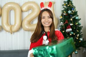 alegre Navidad 2024 concepto asiático mujer son contento y Encantado a recibir Navidad regalos. foto