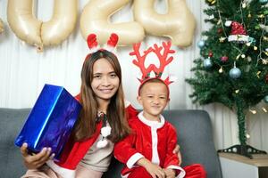 Merry Christmas 2024 concept Boy receives a gift from his mother at christmas photo