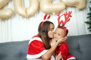 alegre Navidad 2024 concepto madre y niño Decorar el Navidad árbol con vistoso Navidad pelotas. foto