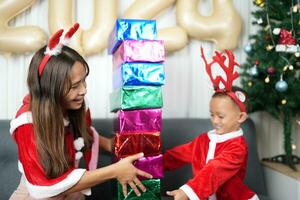 Merry Christmas 2024 concept Boy receives a gift from his mother at christmas photo