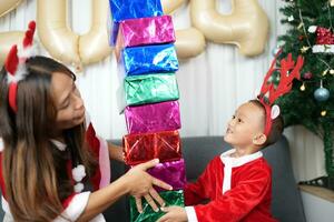 Merry Christmas 2024 concept Boy receives a gift from his mother at christmas photo