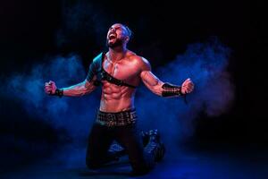 Young and muscular man performing a theatrical pose on stage. photo