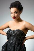 Portrait of beautiful brunette girl in the studio on a gray background in dress photo