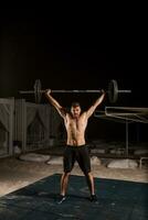 Man makes exercises with barbell photo