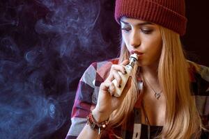 young woman smoking electronic cigarette photo