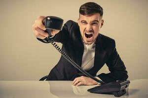 young man dials the phone number while sitting in the office photo