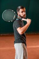 hermoso joven hombre en camiseta con raqueta en tenis Corte foto