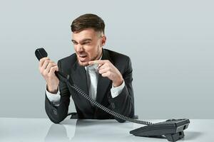 young man dials the phone number while sitting in the office photo