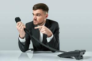 Portrait of attractive businessman holding telephone in his hand. This call is for you concept photo