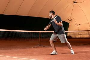 Handsome young man in t-shirt holding tennis racket on tennis court photo