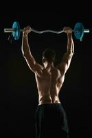 bodybuilder lifting a barbell on black background photo