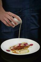 Chef pouring sauce on baked duck breast with beetroot and daikon photo