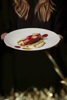 Woman holding plate with roasted duck breast with daikon, beetroot and bechamel photo