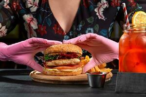 mujer en rosado caucho guantes tomando hamburguesa con Cerdo filete foto