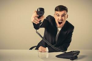 young man dials the phone number while sitting in the office photo