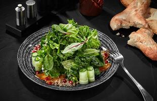 Salad from greens, cucumber, persimmon, walnut dressing and pomegranate photo