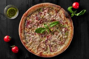 Pizza with cream sauce, mozzarella, bacon, leek and parmesan photo