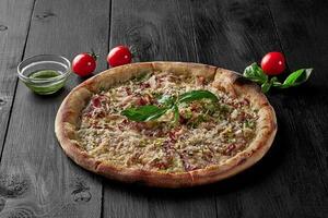 Pizza with cream sauce, mozzarella, bacon, leek and parmesan photo