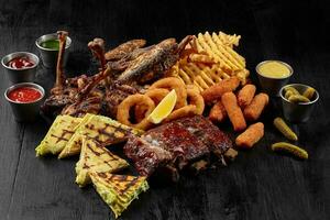 Beer set of pork ribs, chicken, fried fish, cheese sticks, onion rings, fries and burritos photo