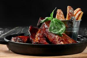 Grilled pork ribs in barbecue sauce with potato wedges photo