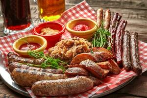 Beer set of grilled sausages with stewed cabbage, potato wedges and sauces photo