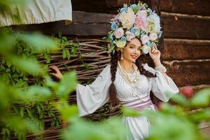 Soft focus. Brunette girl in a white ukrainian authentic national costume and a wreath of flowers is posing against a terrace. photo