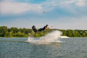 hombre hábilmente haciendo trucos en wakeboard en verano día foto