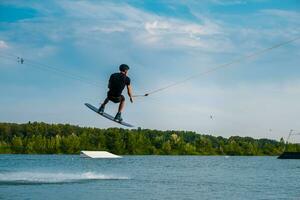 hombre practicando técnica de saltando durante wakeboard formación foto