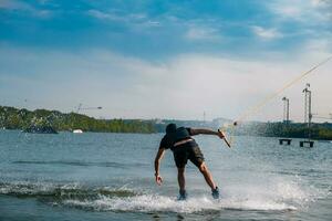 Back view of man balancing on wakeboard on river photo