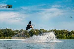 Wakeboard rider towed on cable jumping in open water photo