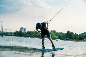 Man balancing on wakeboard on river surface in city photo