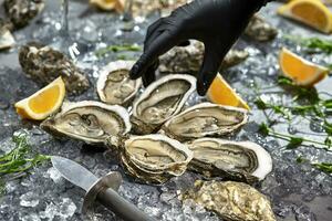 Hand in glove reaching for oysters served in open shells photo