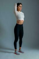 Slim girl doing stretching workout on grey background photo