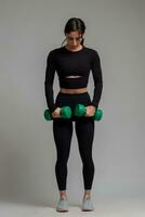 Focused girl ready to do exercises with dumbbells on grey background photo