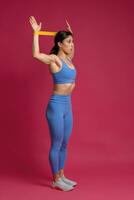 Girl exercising with resistance band loop on maroon background photo