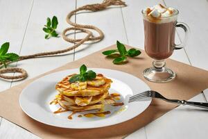 Pancakes with banana, caramel syrup served with hot cocoa photo