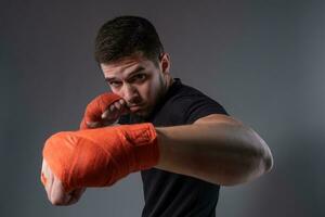 joven combatiente ejecutando izquierda pinchazo con mano envuelto en boxeo cinta foto