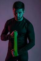 Athletic young man performing exercises with resistance band photo