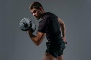 Focused strong guy performing bicep curls with dumbbell photo