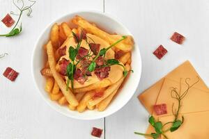 Crispy french fries with cheese sauce and fried bacon photo