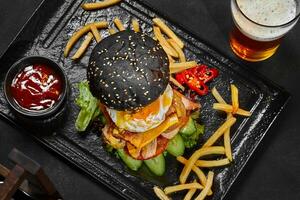 Large black cheeseburger with vegetables, chicken, caramelized onion, fried egg and bacon photo