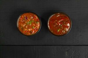 Tomato sauces in glass dipping bowls on black wooden background photo