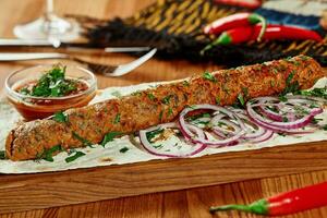 Lamb kebab with thin lavash, fresh onion and satsebeli sauce photo
