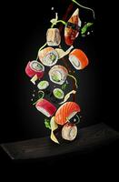 Sushi with garnishes and soy sauce hovering over plate on black background photo