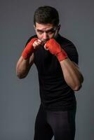 Man with wrist wraps on hands standing in orthodox boxing stance photo