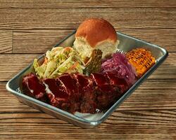 Baked pork loin with barbecue sauce and vegetable garnish on plastic tray photo