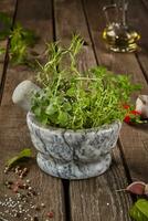 Fragrant herbs in mortar on wooden table with condiments and oil photo