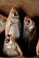 salado aire seco pescado envuelto en genuino cuero en de madera antecedentes foto